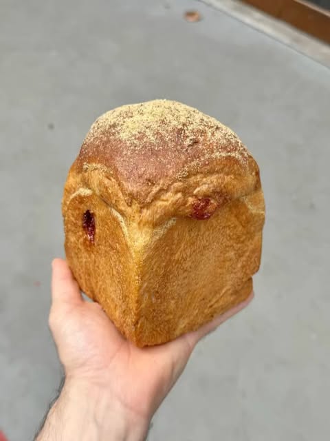 Pão artesanal dourado da Odara, segurado na mão