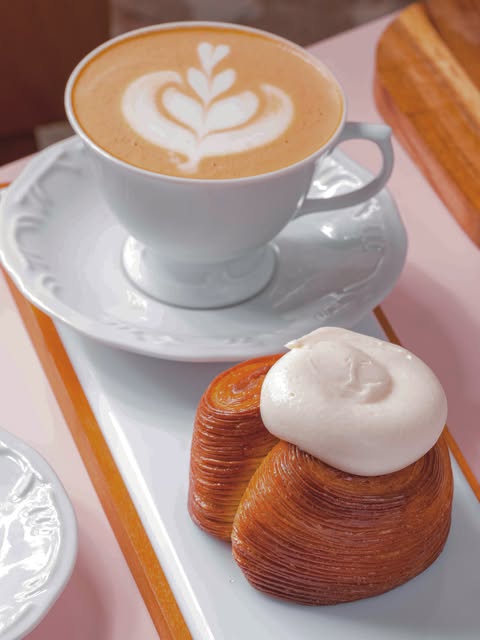 Café com latte art e folhado da Odara sobre uma mesa